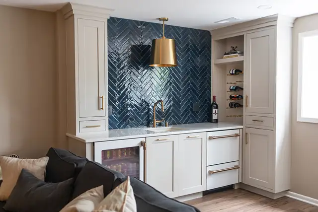 Finished basement in Madison, WI with a wet bar, navy herringbone tile wall, brass pendant, wine rack and beverage fridge