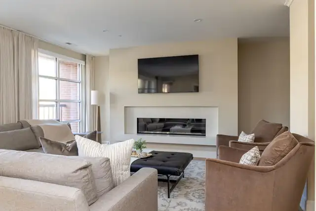 Living room in a complete Madison, WI condo renovation with a linear gas fireplace and wall-mounted TV