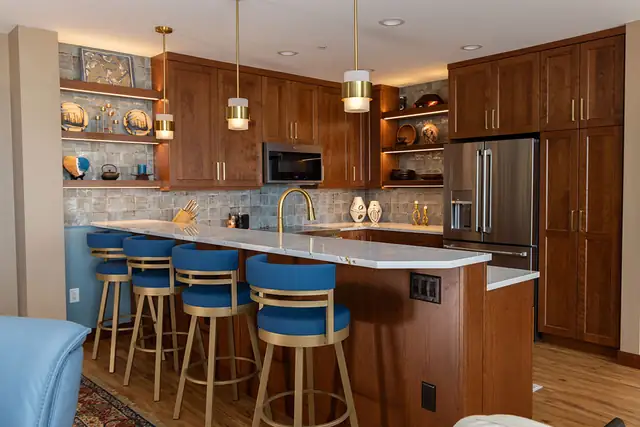 Madison, WI condo kitchen with cherry cabinets, brass pendants, lit open shelving and blue swivel stools at the peninsula
