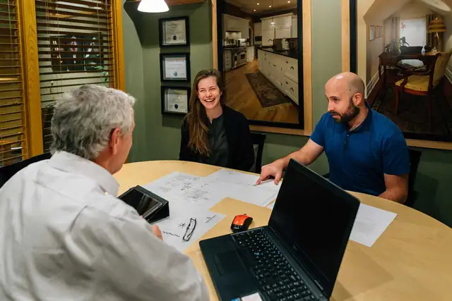 Sweeney team members reviewing plans with a homeowner at a round table in the office
