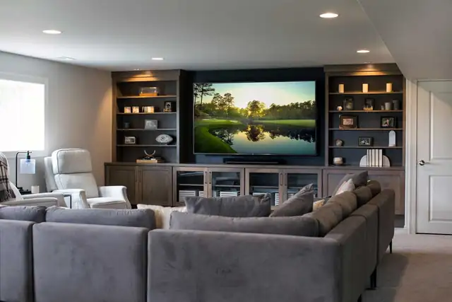 Sun Prairie, WI home addition living room with built-in shelving around the TV, recessed lights and a gray sectional