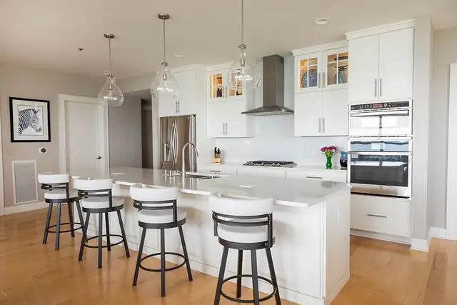 Traditional condo kitchen remodel in Madison, WI with white shaker cabinets, glass pendants and island seating for four