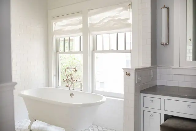 Primary bathroom in a Madison, WI whole-home remodel with a clawfoot tub, white subway tile and tall double-hung windows
