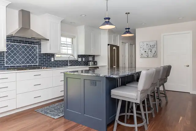 Whole-house remodel kitchen in Madison, WI with a navy island, blue tile backsplash, stainless hood and hardwood floor